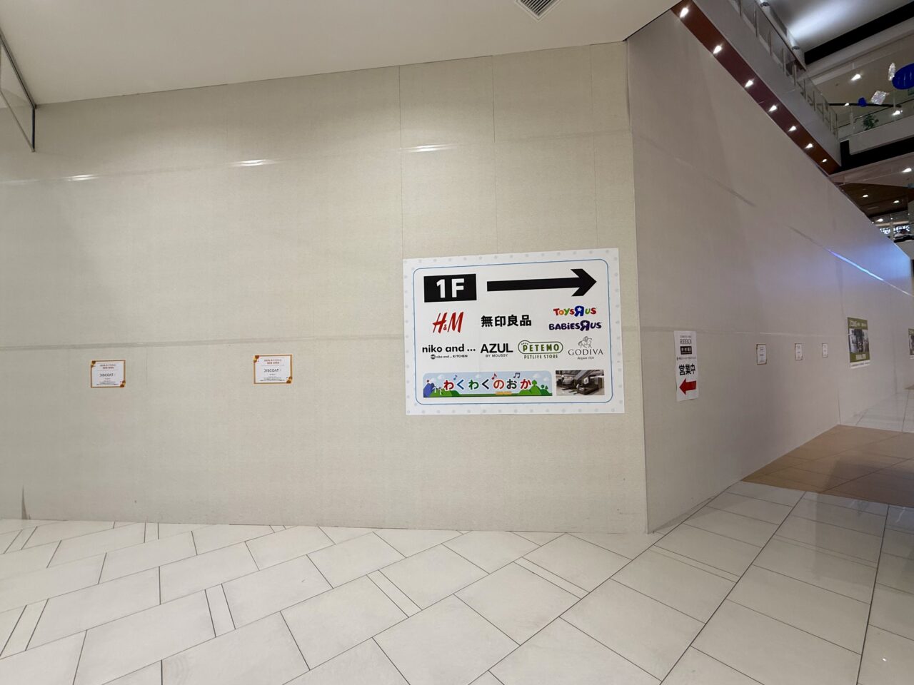 イオンモール甲府昭和1階 3COINS+plus移転先の工事中の仮囲い まだ店舗はなくボードが立つ(2026年7月18日撮影)