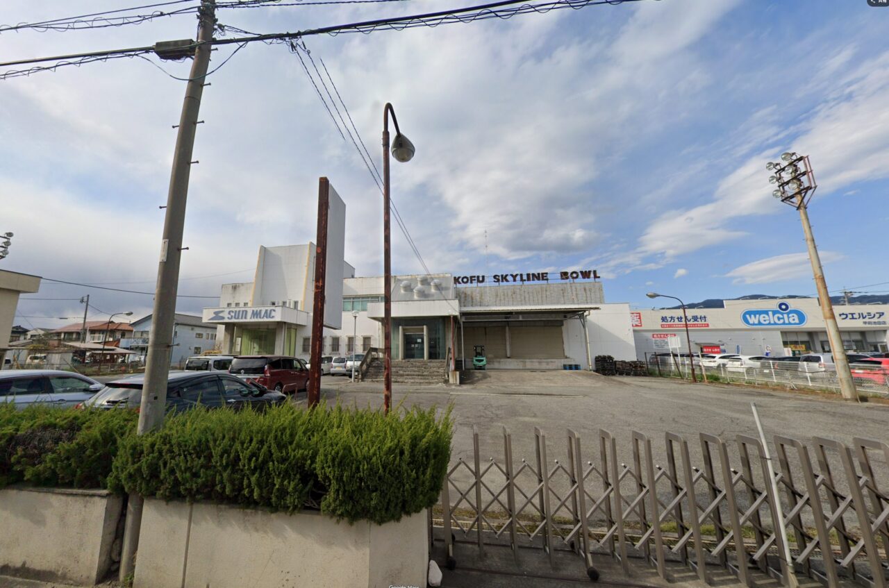 解体される前の建物。屋上にKOFU SKYLINE BOWLの看板、入口にSUN MACのロゴが見える。右奥はウエルシア甲府池田店(Googleストリートビュー・2025年4月時点/©2025 Google)