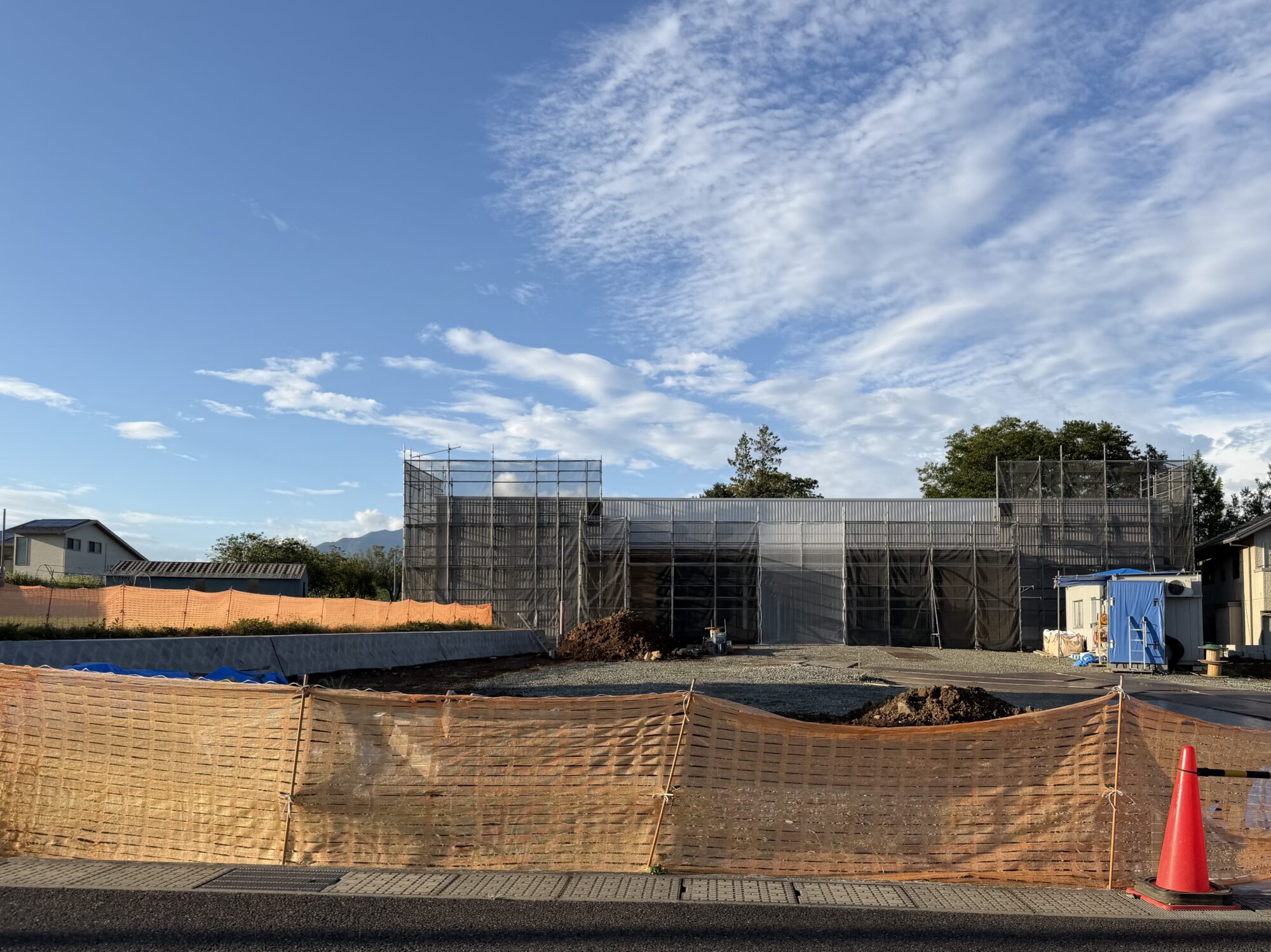 外壁が張られて形が見えてきた建設中の建物 足場と養生シートに覆われている 甲斐市龍地(2026年8月12日撮影)