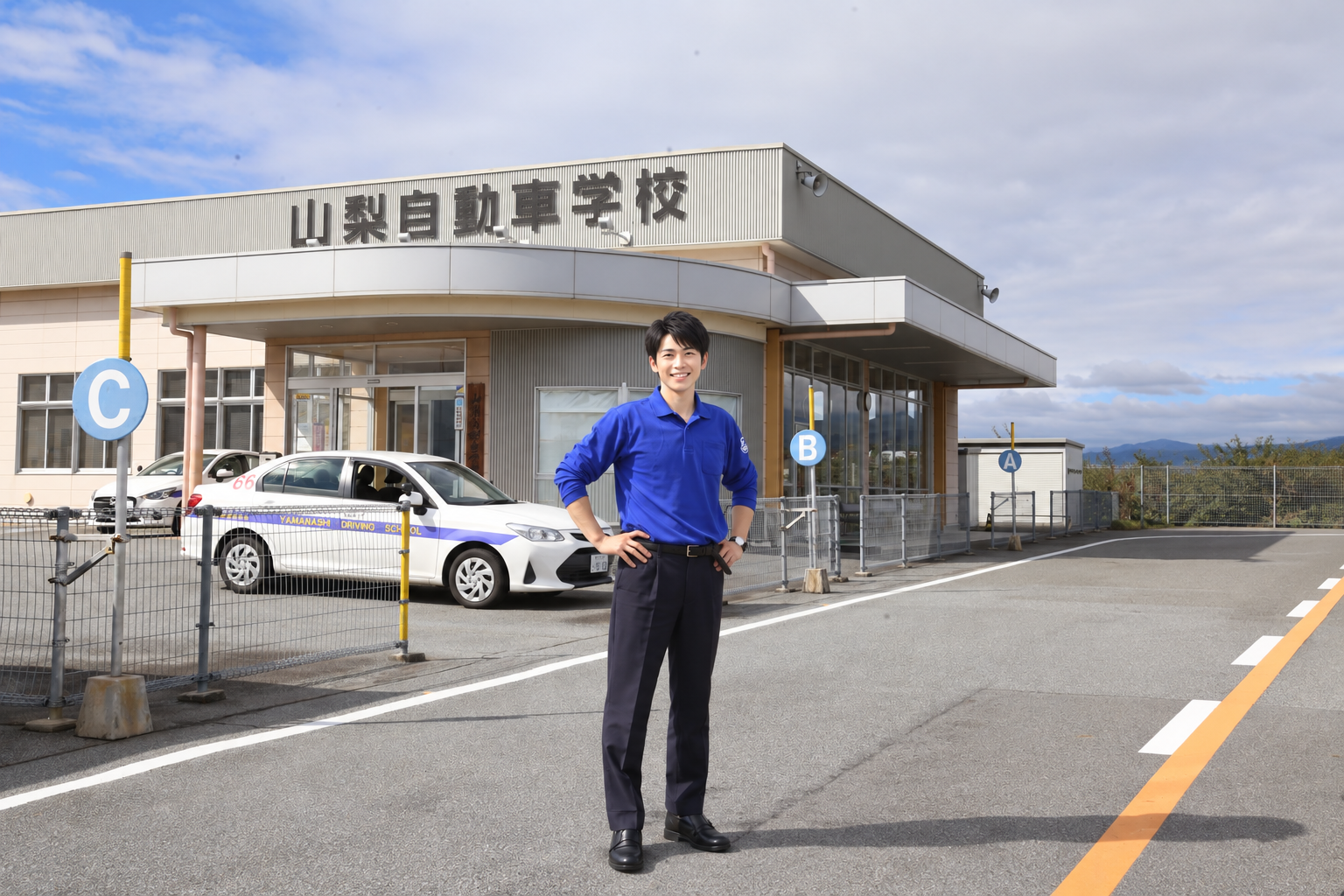 山梨自動車学校の建物前に立つ指導員のイメージ