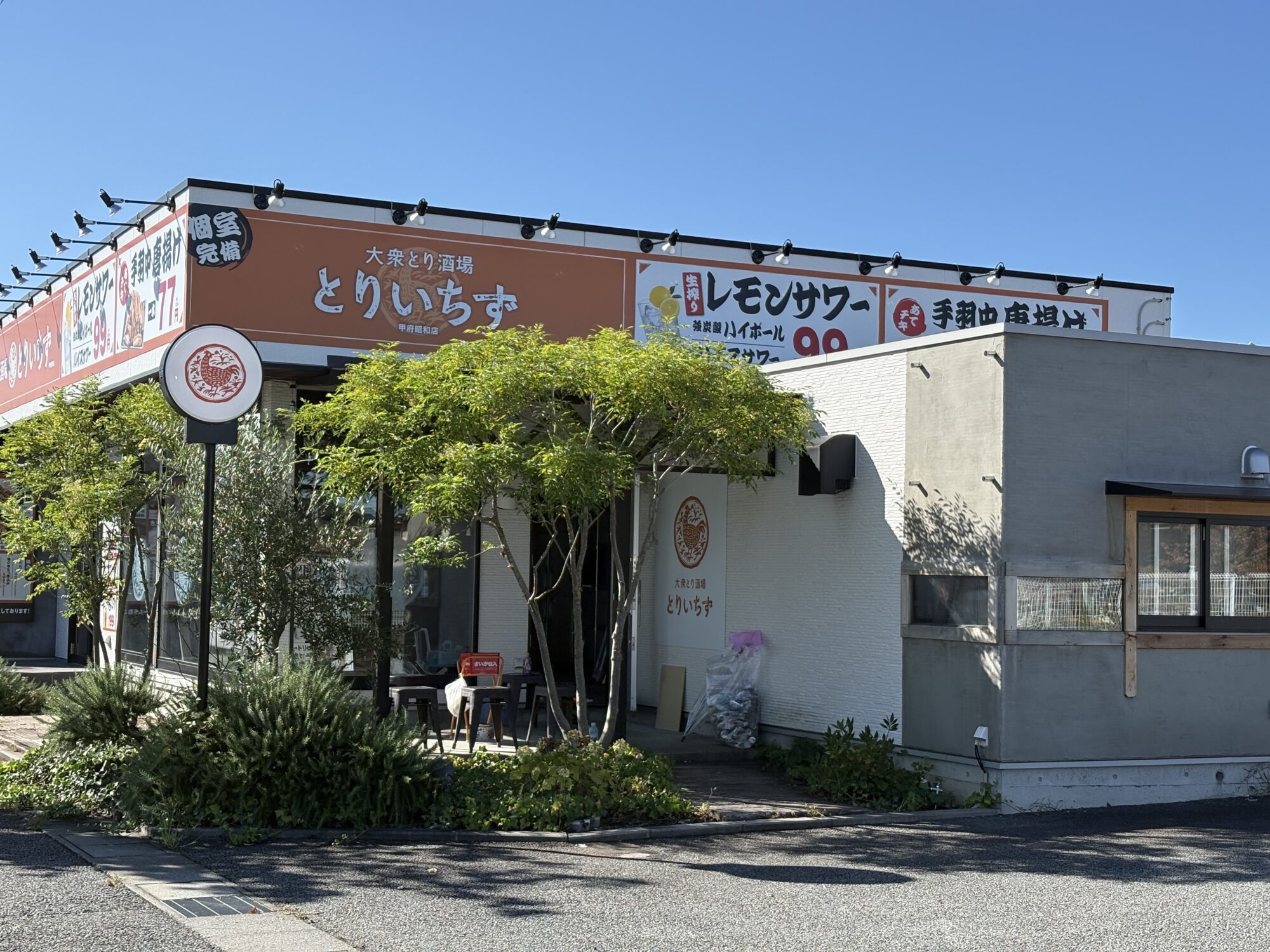 とりいちず 甲府昭和店を横から見た外観。オレンジ色の看板と鶏のマークの丸いサイン(2026年10月1日撮影)
