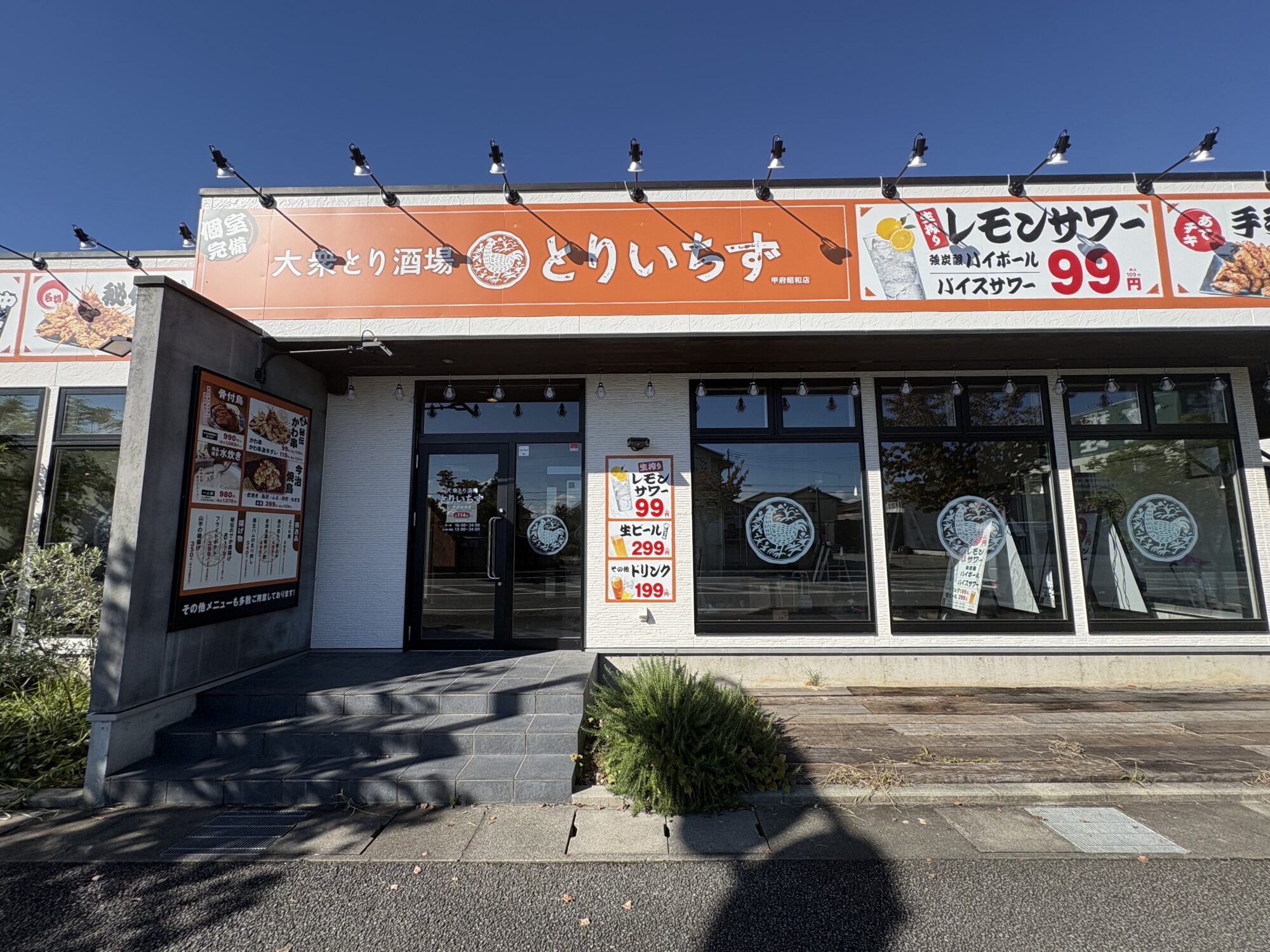 嵜本の跡に看板が付いたとりいちず 甲府昭和店の正面。入口の横にメニュー看板、窓に鶏のマーク(2026年10月1日撮影)