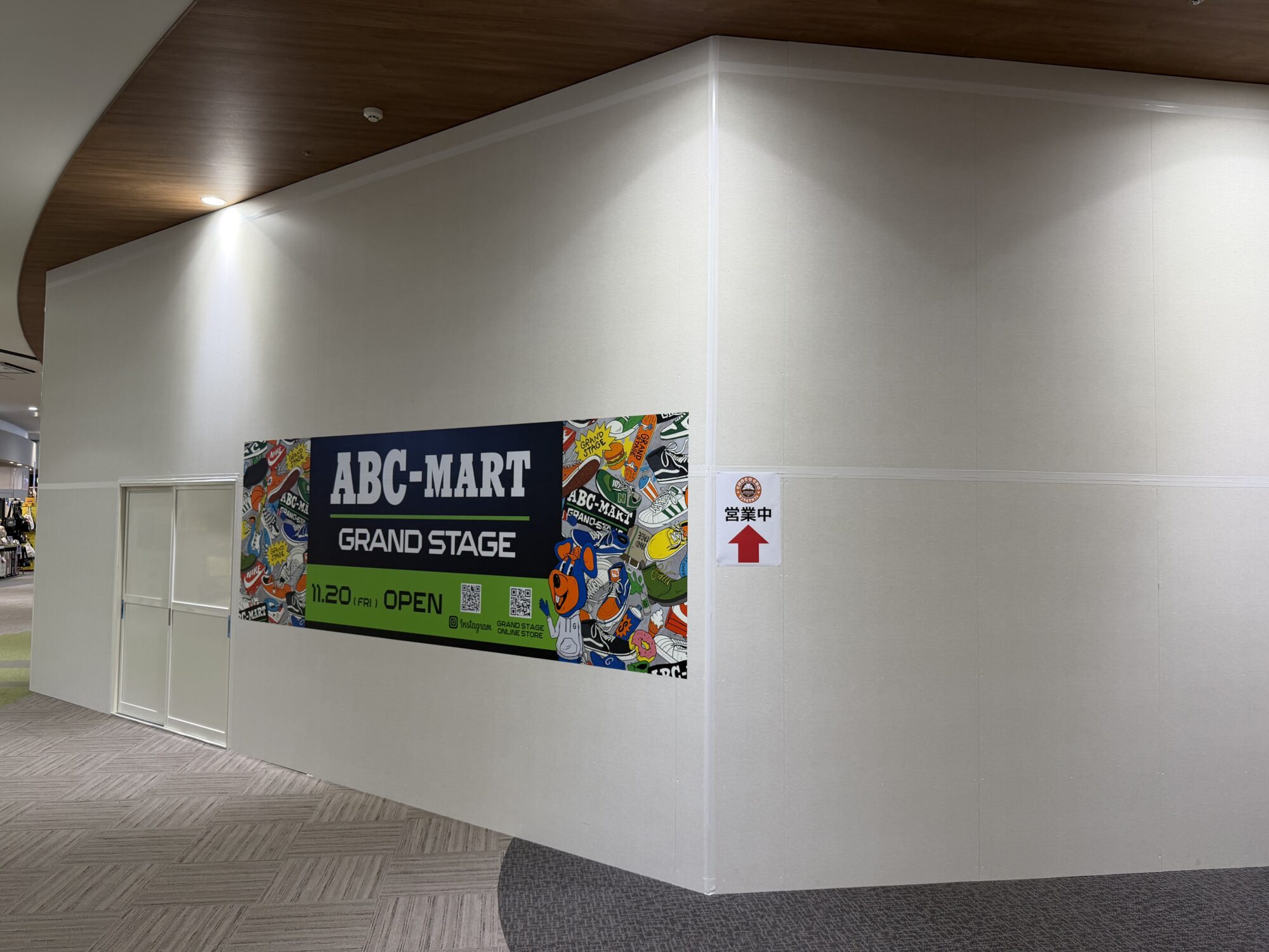 イオンモール甲府昭和2階の仮囲いに貼られたABC-MART GRAND STAGEの告知看板を斜めから（2026年10月12日撮影）